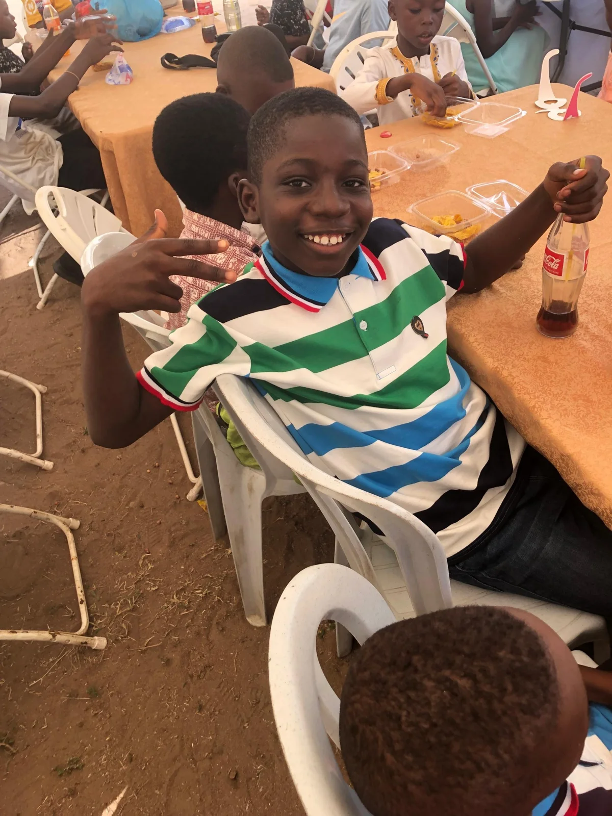 A smiling child seated at a table during a community celebration.